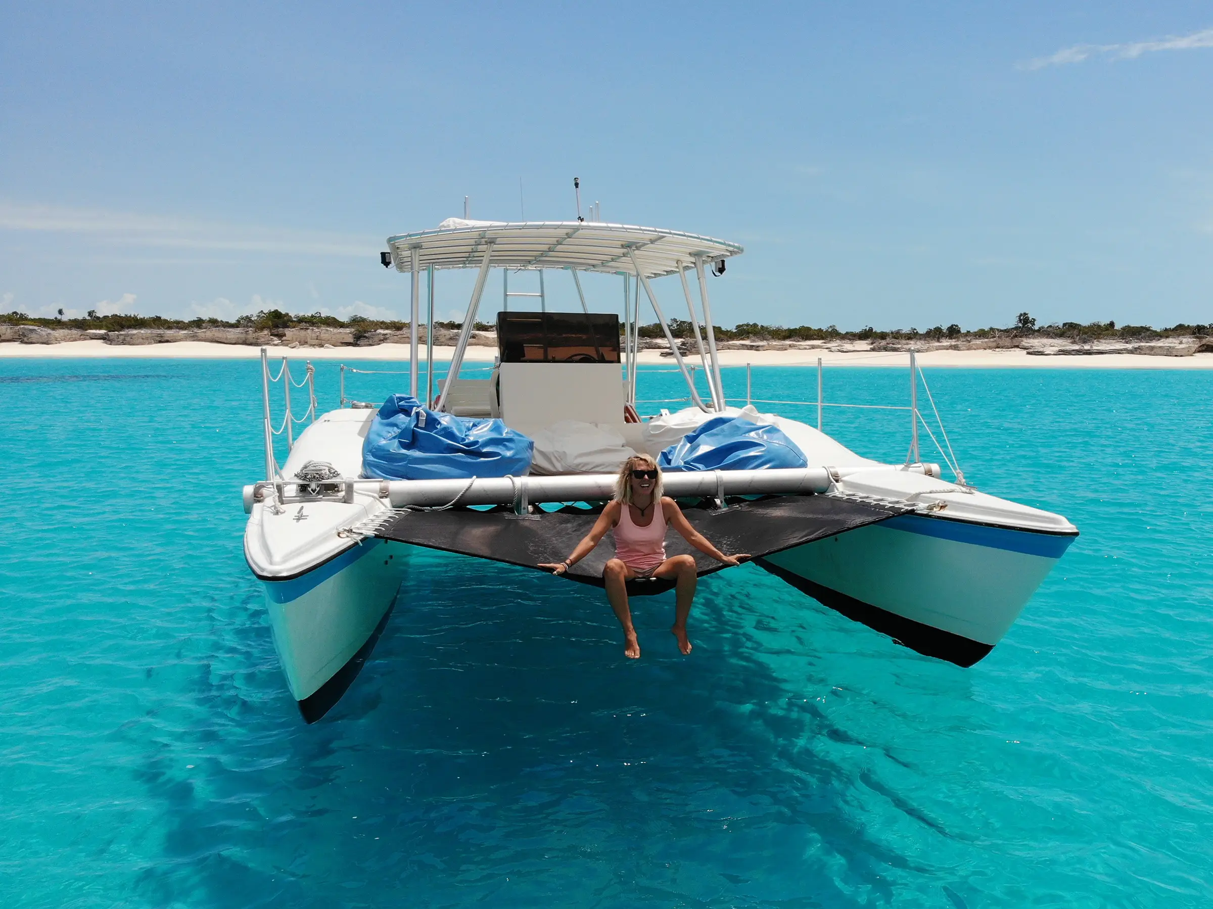 Catalyst, a white motor catamaran, anchored in turquoise water off a Caicos Cays beach