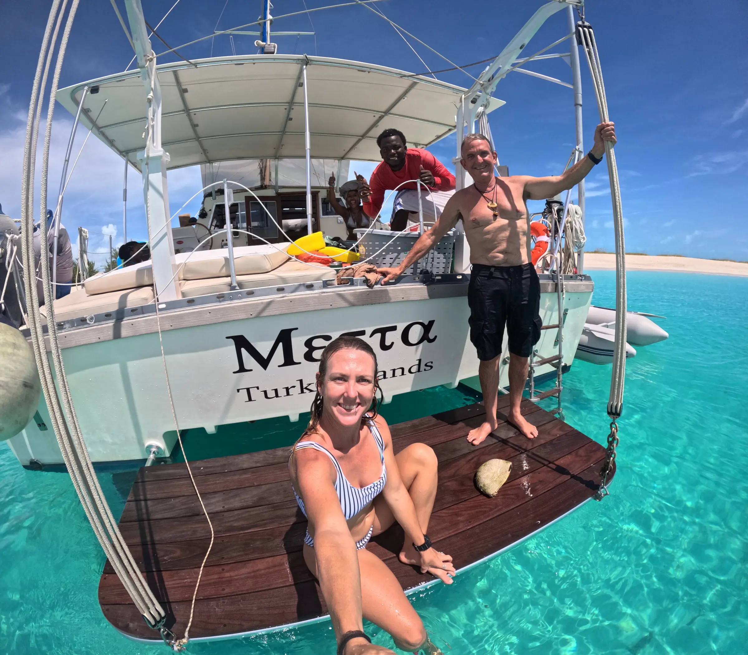 Guests on Metta's bow over clear water