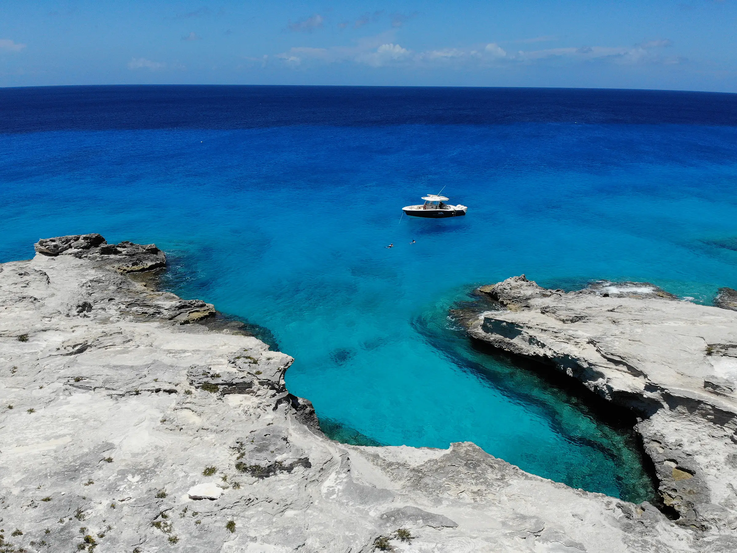 Sweet T anchored in a deep blue bay between limestone cliffs