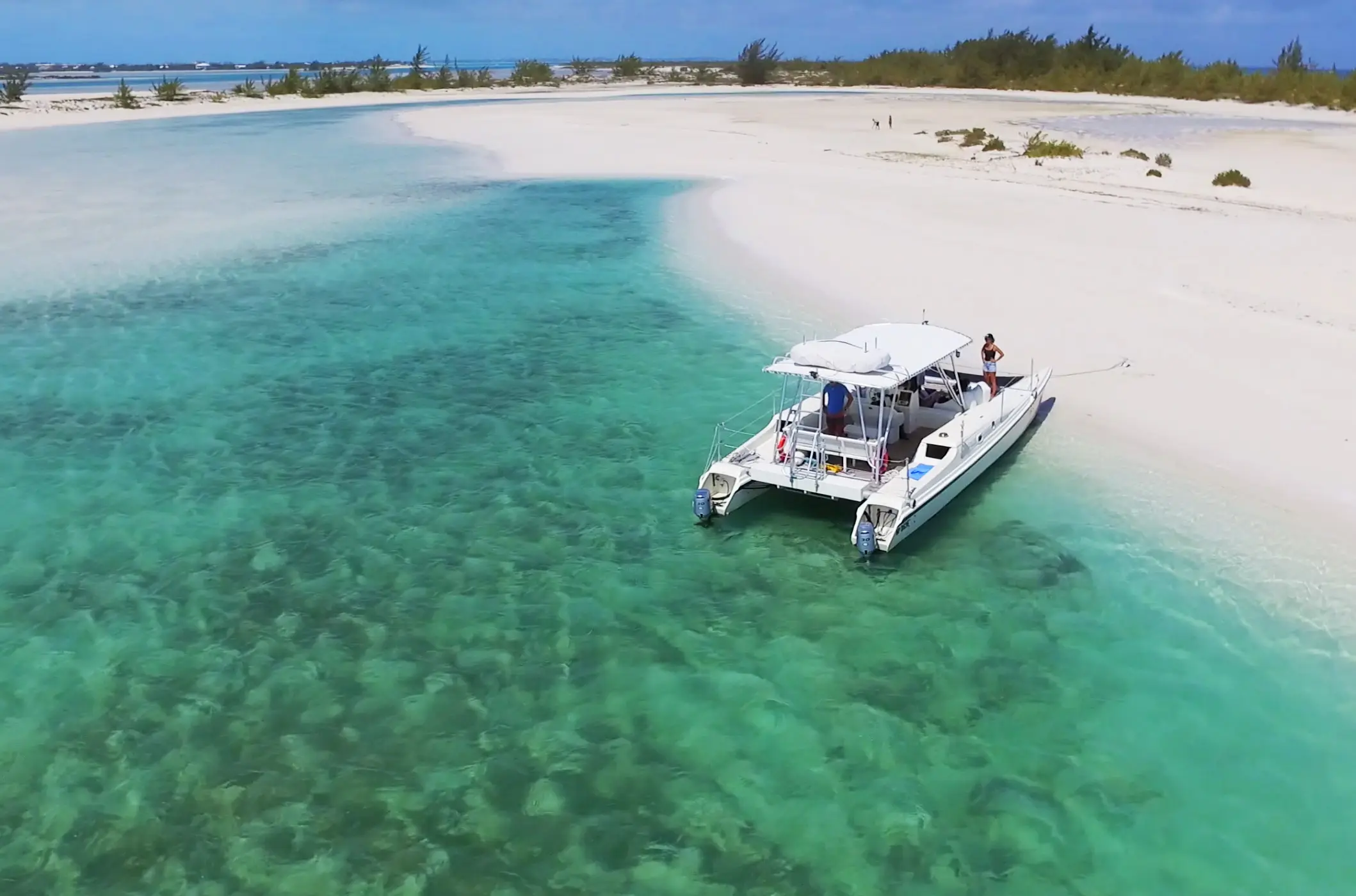 Aerial view of a Caicos Catalyst catamaran on a sandbar beside a white beach
